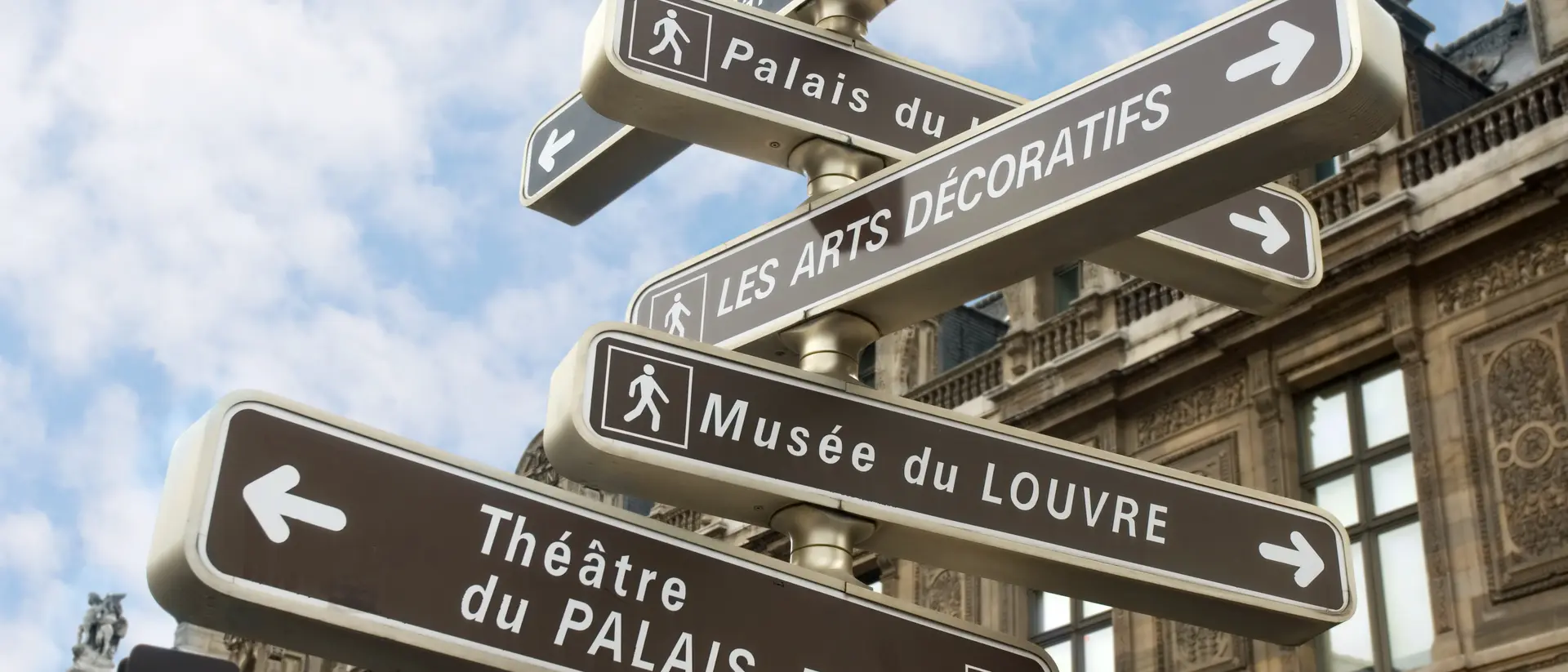 Signpost with directional arrows indicating landmarks: Palais du Louvre, Théâtre du Palais-Royal, Les Arts Décoratifs.
