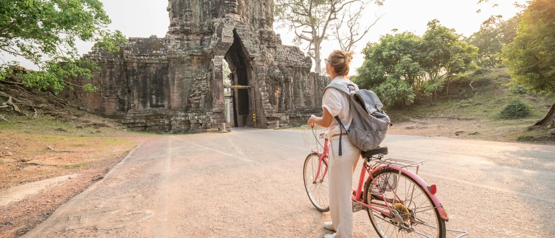 Angkor Wat Young woman traveling in Cambodia visiting the temples of Angkor wat complex by bicycle.