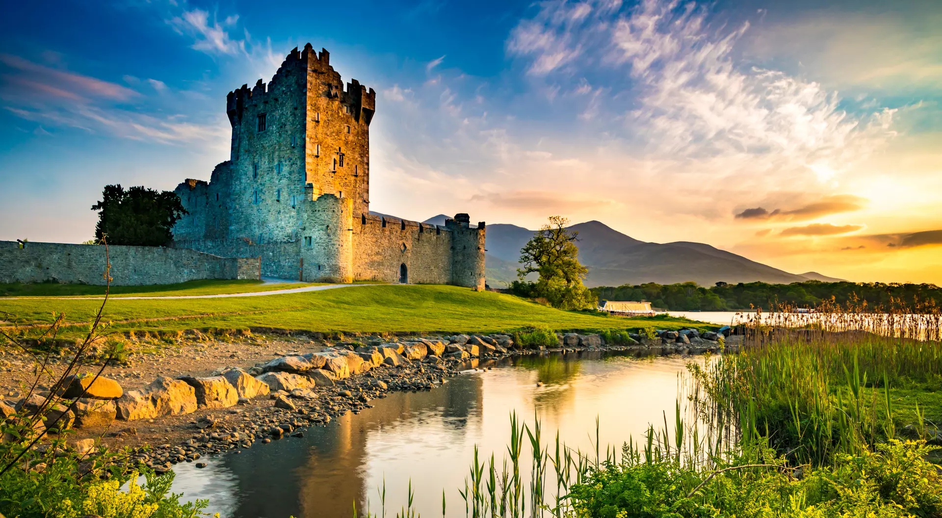 Ancient old Fortress Ross Castle ruin with lake and grass in Ireland during golden hour