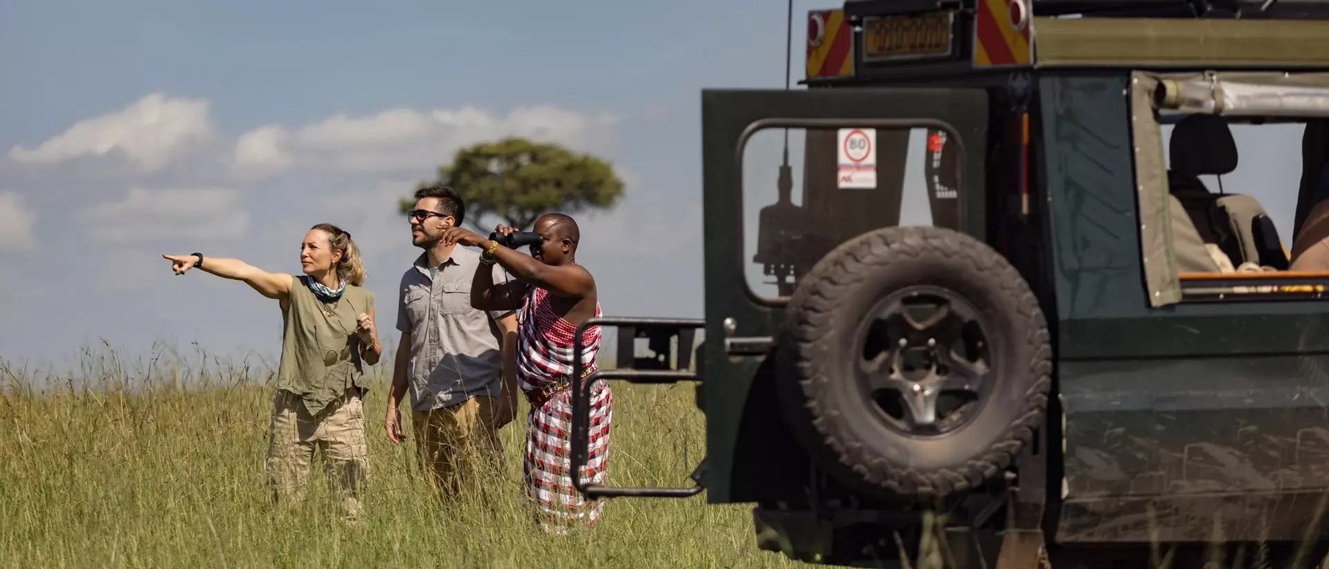 Two travellers with a Maasai tracker guide on safari in Kenya.