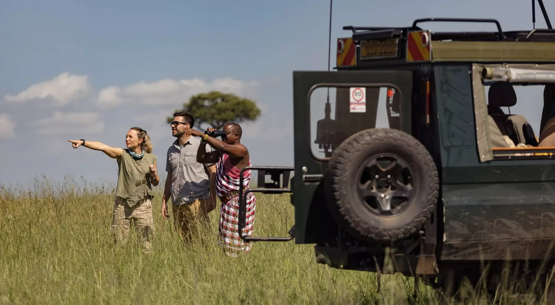 Two travellers with a Maasai tracker guide on safari in Kenya.