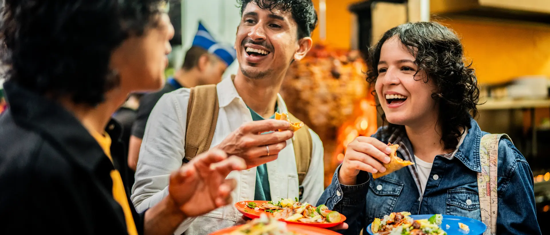 Three young people enjoy tacos in the streets of Mexico City