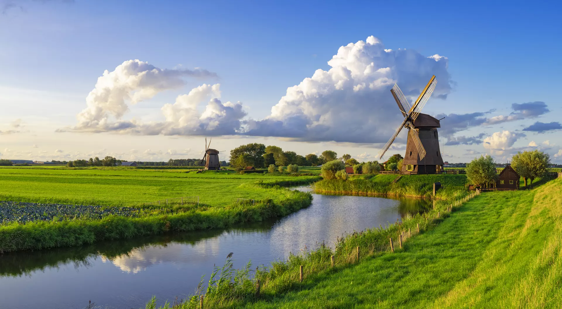 A view of a windmill alongside a canal and farm fields