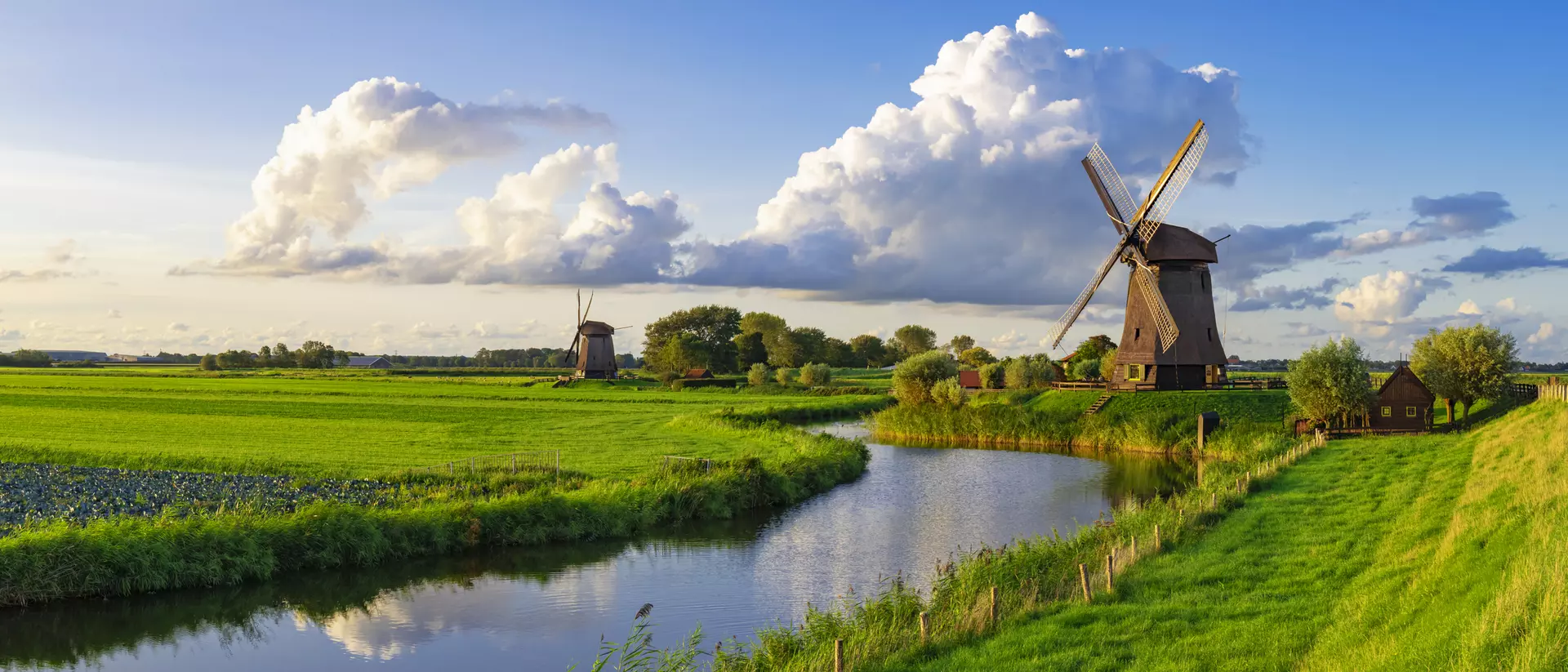 A view of a windmill alongside a canal and farm fields