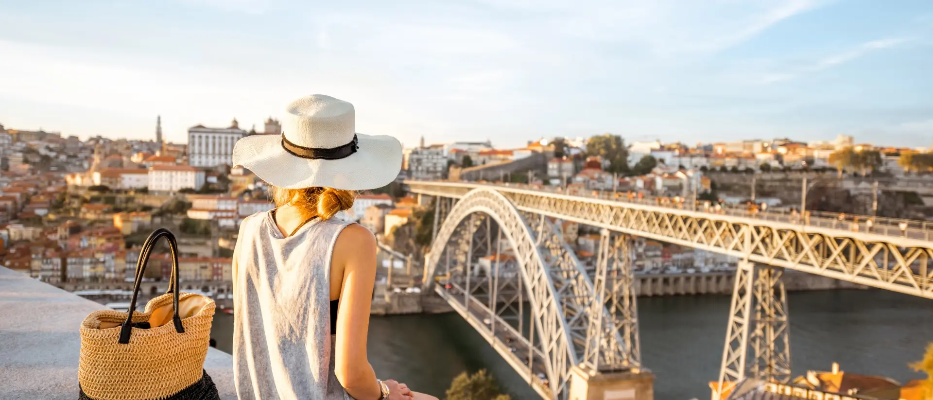 Porto, Portugal a woman sitting on a ledge looking over river and bridge in Porto