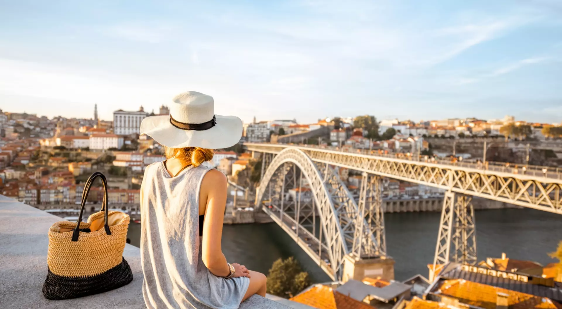Porto, Portugal a woman sitting on a ledge looking over river and bridge in Porto