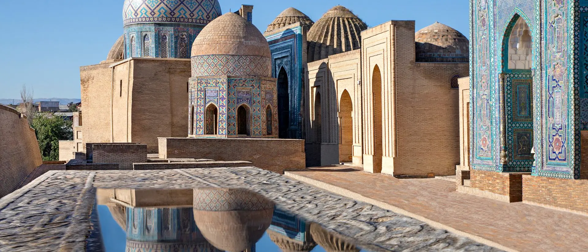 Samarkand, Uzbekistan Mausoleums and domes of the historical cemetery of Shahi Zinda and their reflections in puddle, Samarkand, Uzbekistan.