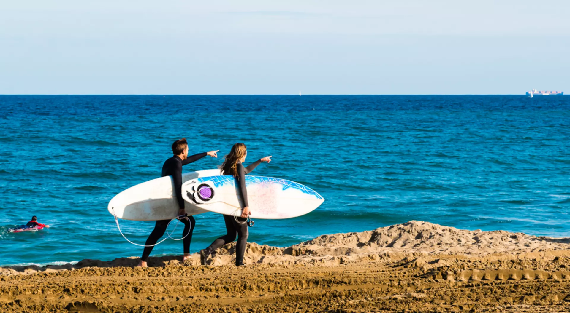 Surfers walking Along the Beach