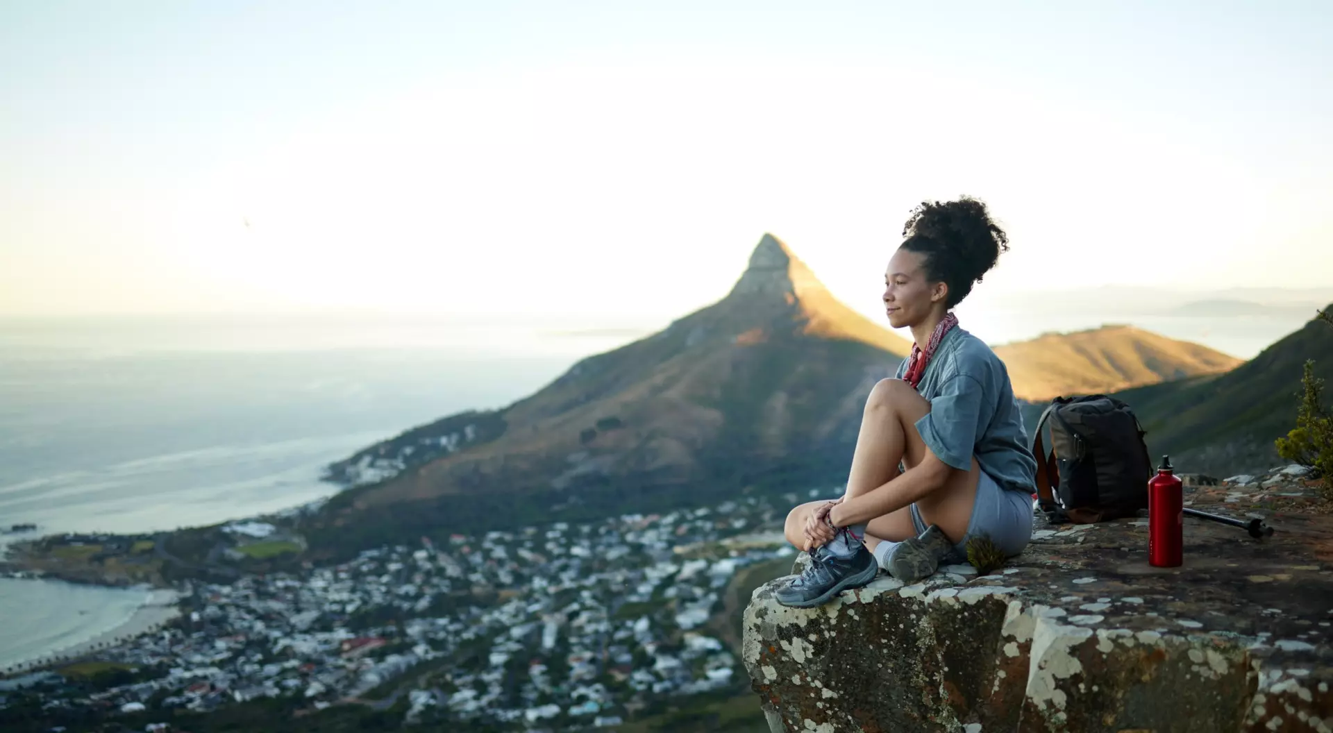 woman on the edge of a mountain overlooking city and ocean