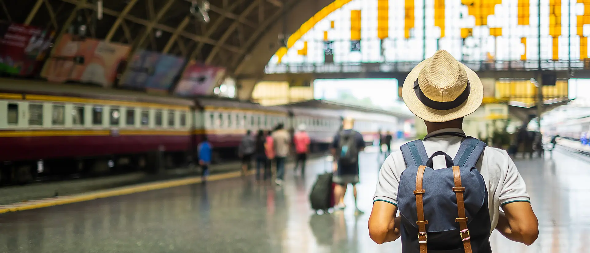 man with a hat and backpack in a train station on the platform