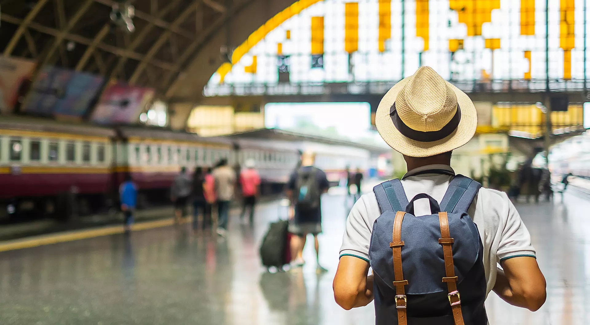 man with a hat and backpack in a train station on the platform