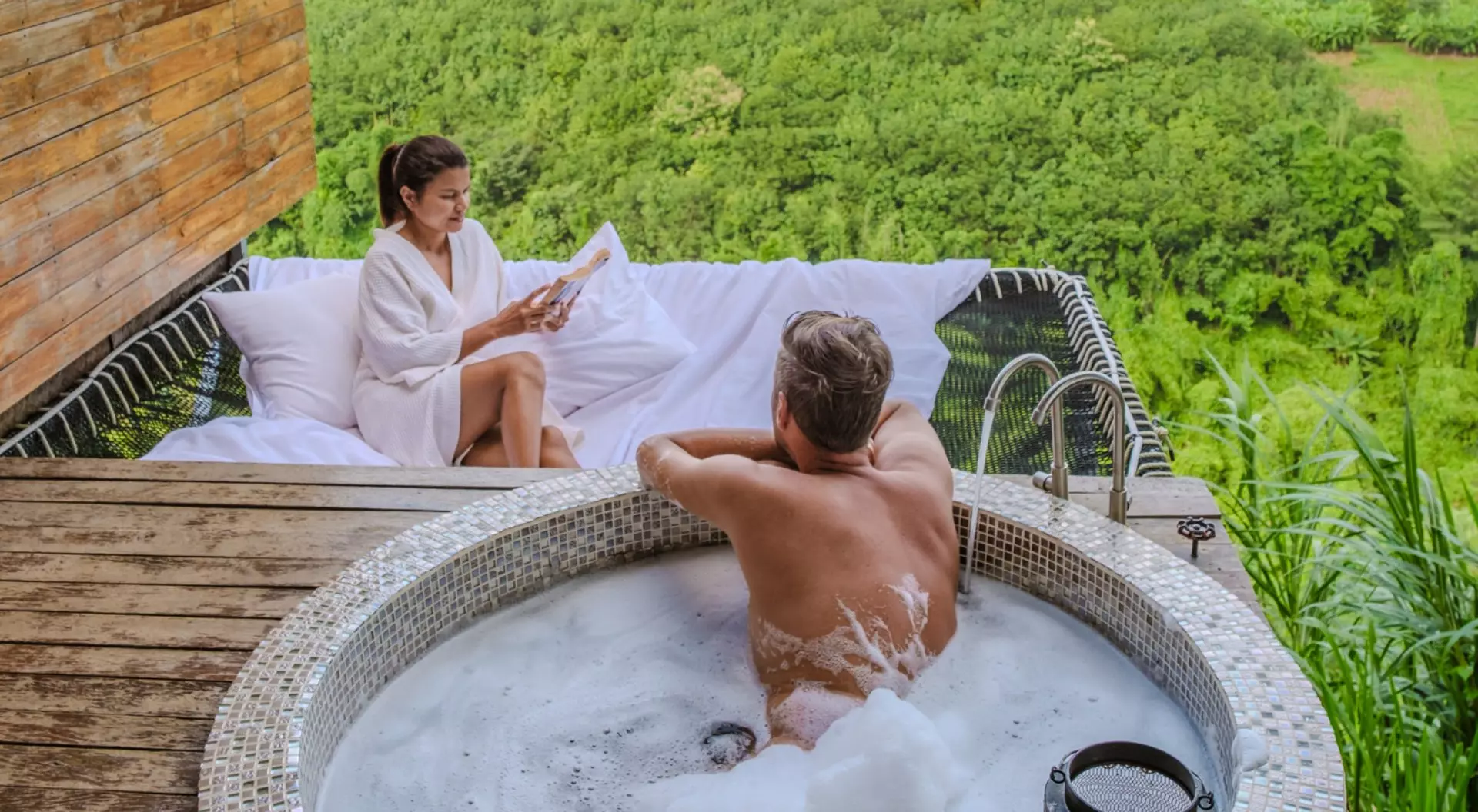 A couple relaxes in a hot tub and a hammock overlooking the hills of northern Thailand.