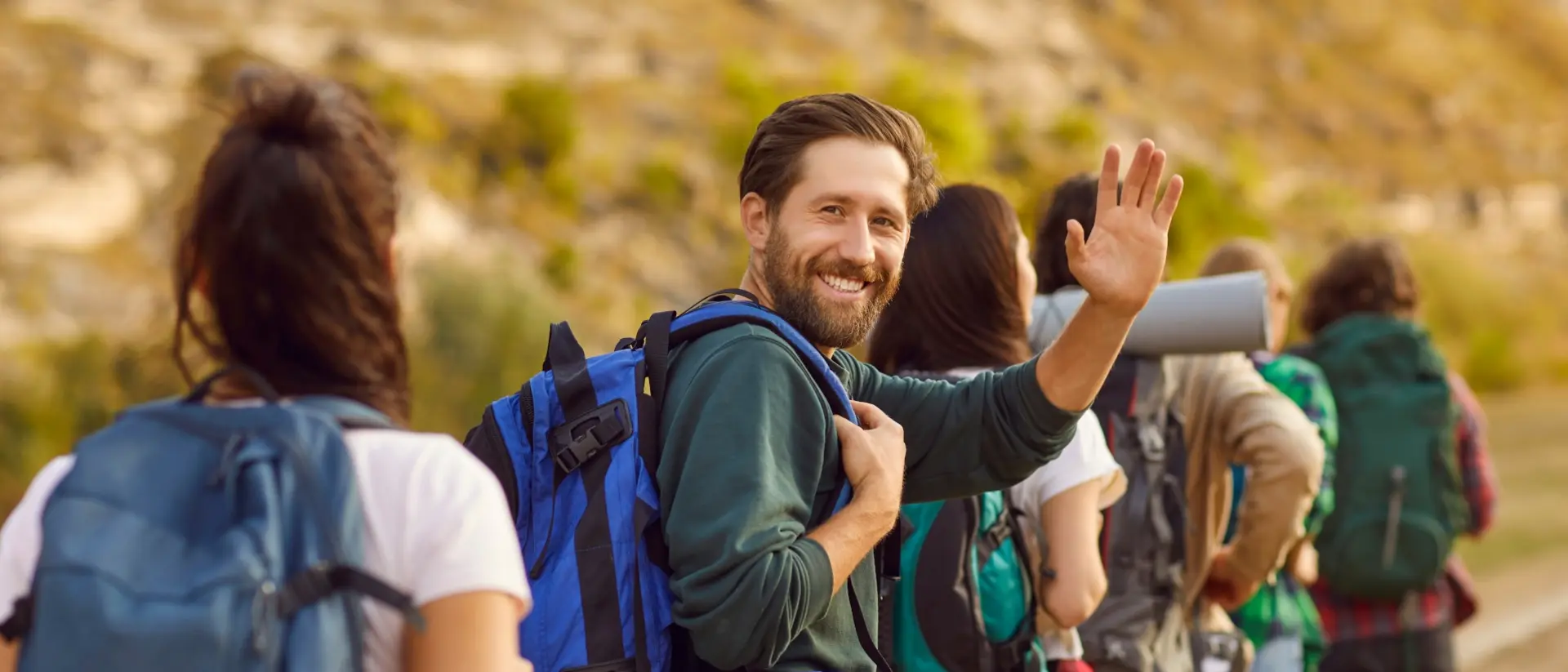 smiling man with a beard packing with others and looking at camera