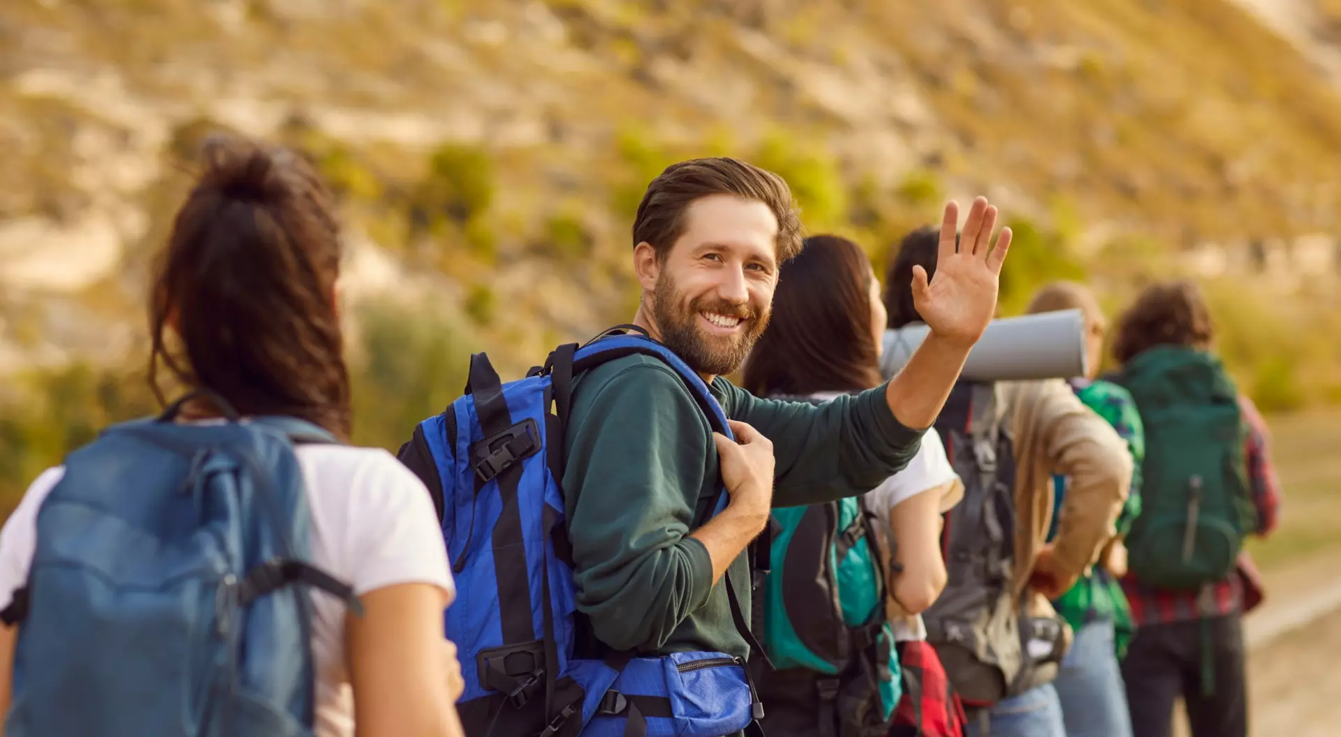 smiling man with a beard packing with others and looking at camera