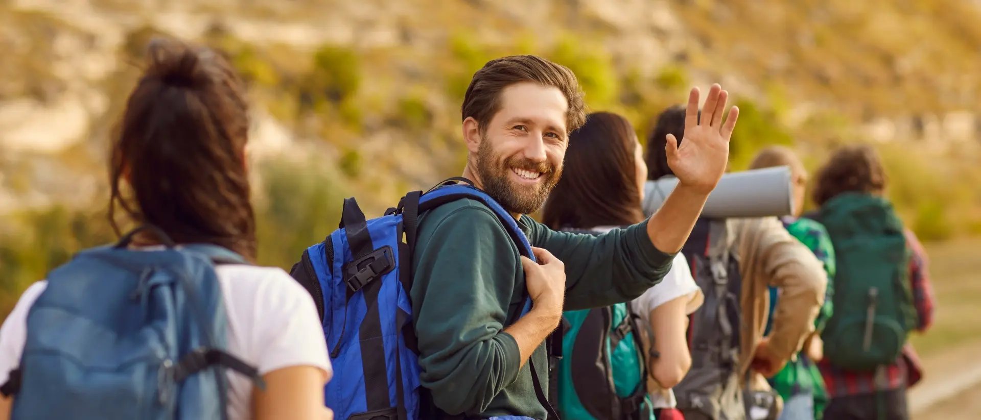 smiling man with a beard packing with others and looking at camera
