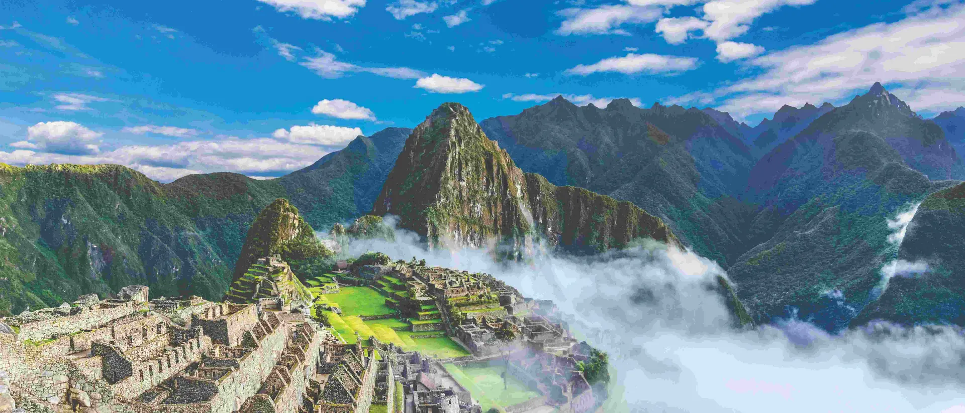 ruins of machu picchu draped in mist with backdrop of mountains