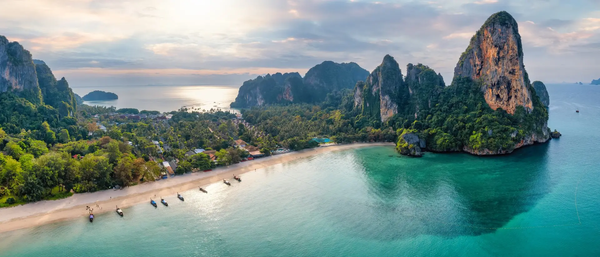 Panoramic aerial view of the beautiful Railay beach, lush rain forest and emerald sea during morning sunrise without people