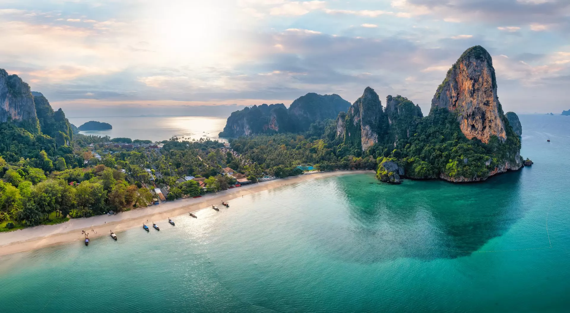 Panoramic aerial view of the beautiful Railay beach, lush rain forest and emerald sea during morning sunrise without people