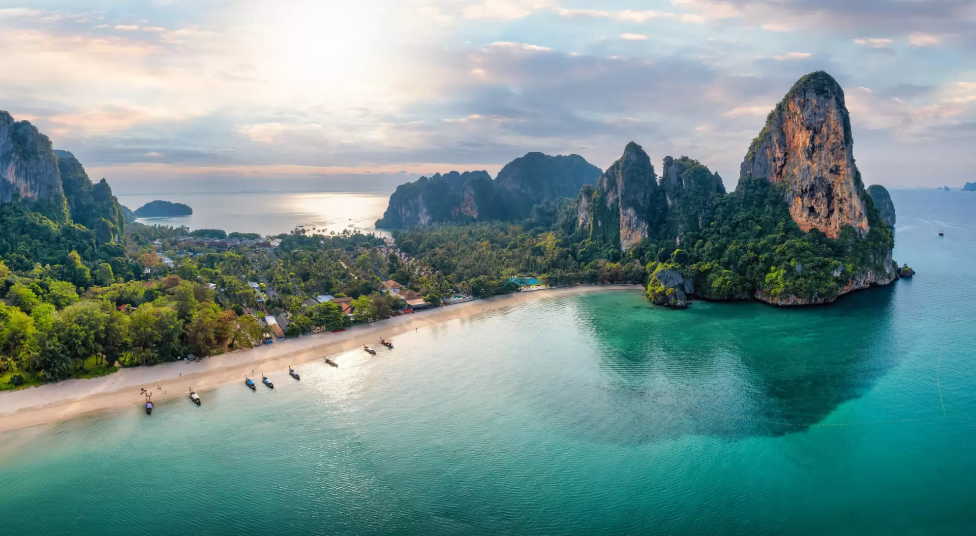 Panoramic aerial view of the beautiful Railay beach, lush rain forest and emerald sea during morning sunrise without people