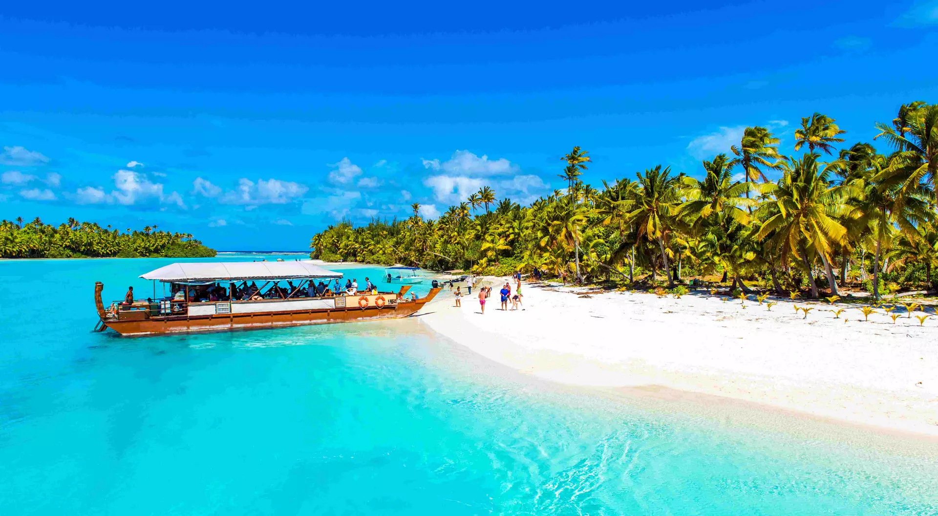 a boat moored next to a white sand beach on a tropical island