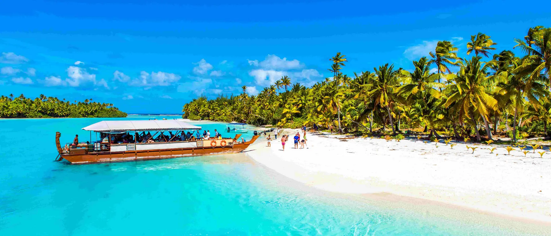 a boat moored next to a white sand beach on a tropical island