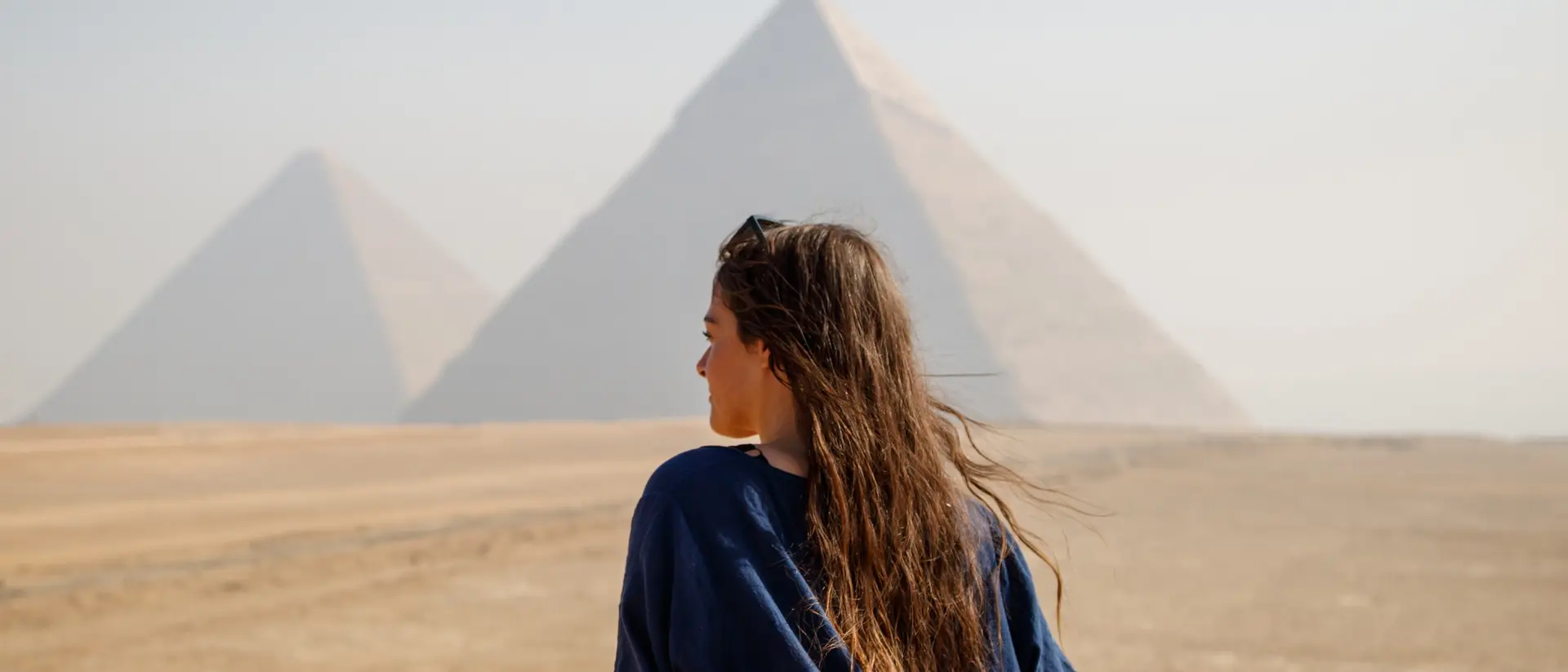 Long-haired woman standing on her back looking at the pyramids of Giza, Egypt