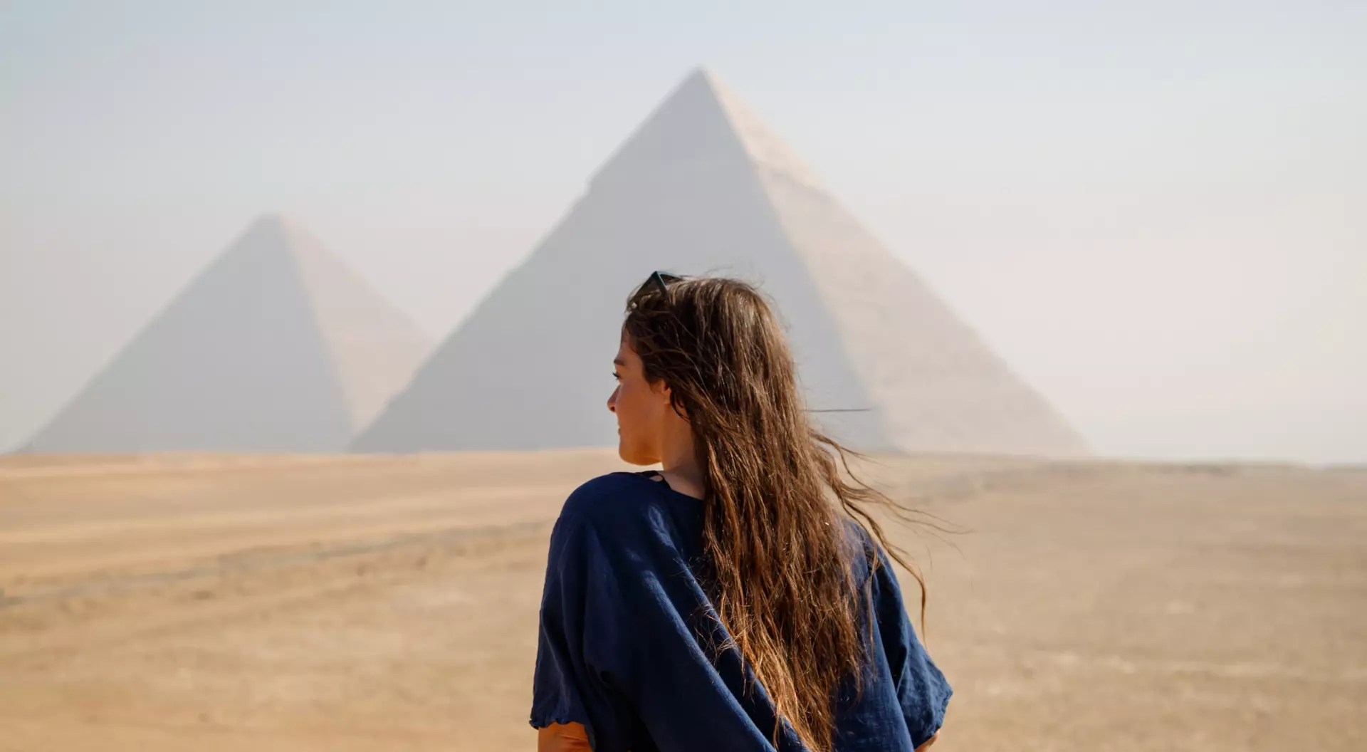 Long-haired woman standing on her back looking at the pyramids of Giza, Egypt