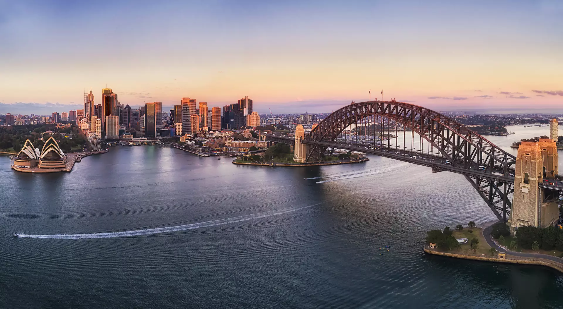Colourful sky over Sydney city CBD high-rise towers at sunrise around Sydney harbour and the Sydney Harbour bridge in elevated aerial view.