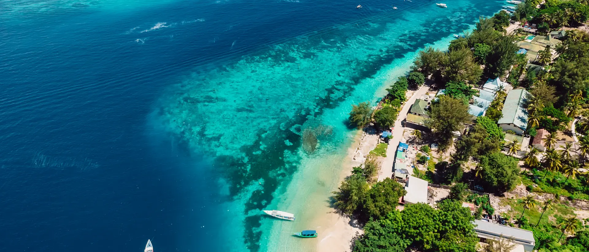 Tropical island with beach, boats and turquoise crystal ocean, aerial view. 