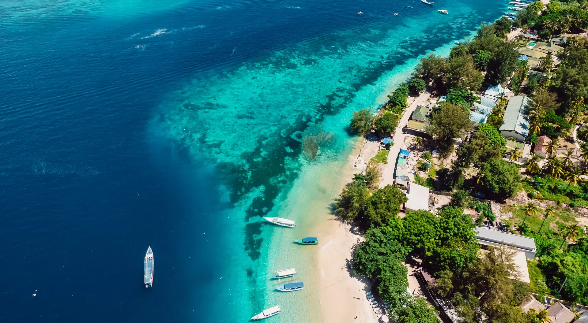 Tropical island with beach, boats and turquoise crystal ocean, aerial view. 