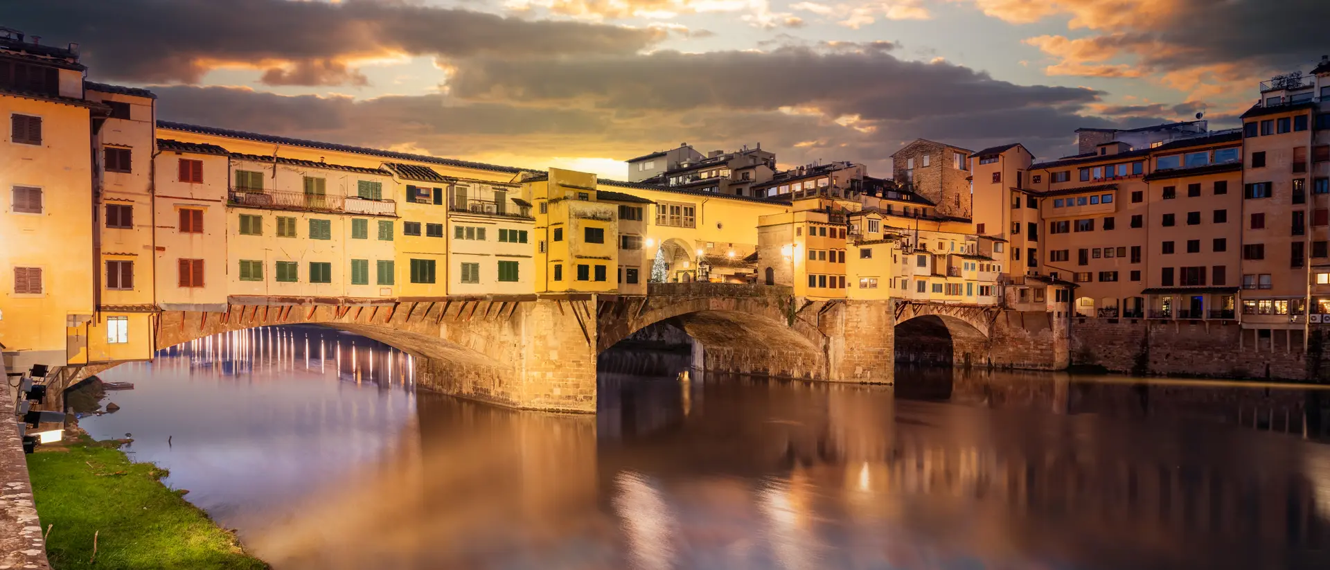 The Ponte Vecchio Bridge crossing the Arno River at twilight.