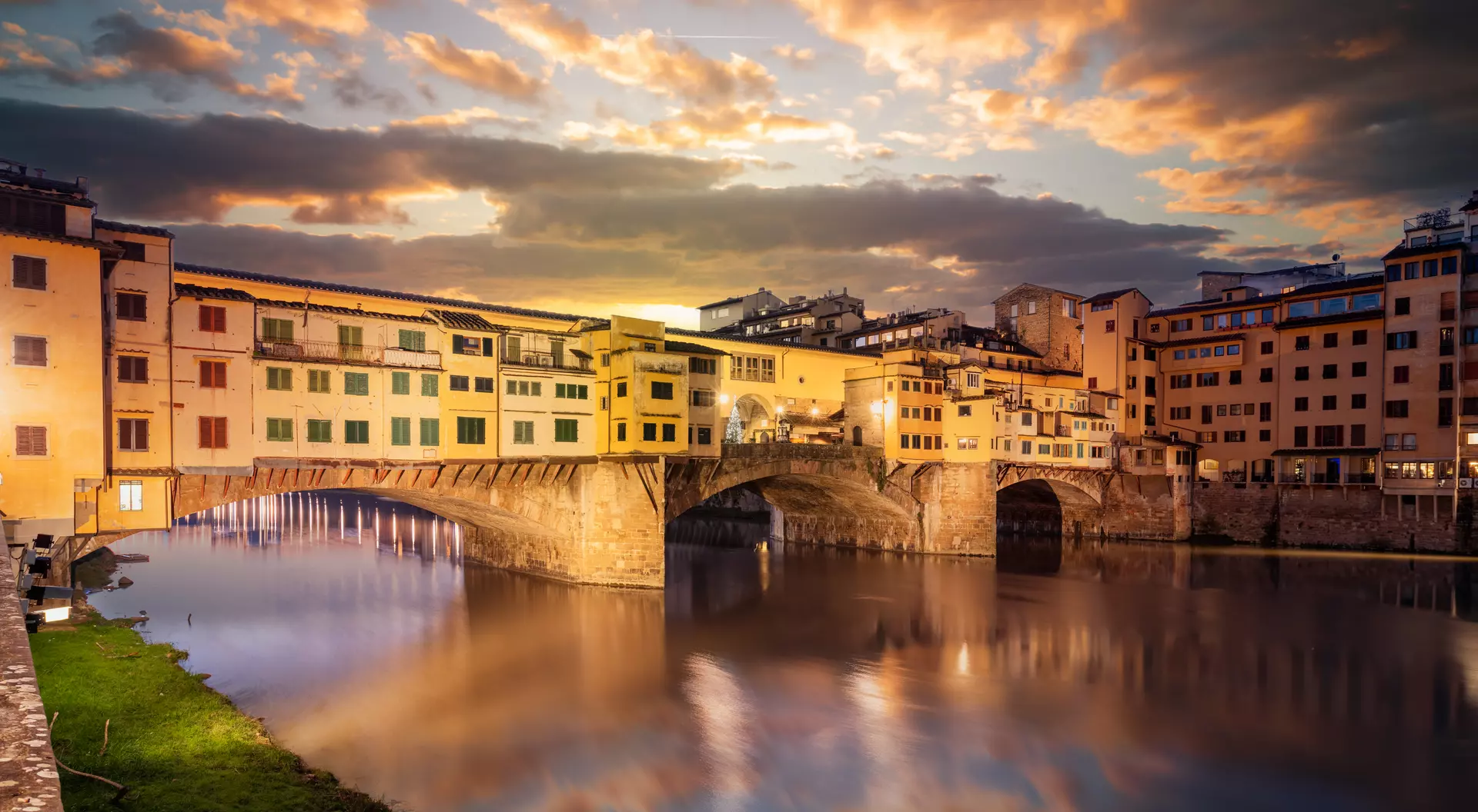 The Ponte Vecchio Bridge crossing the Arno River at twilight.