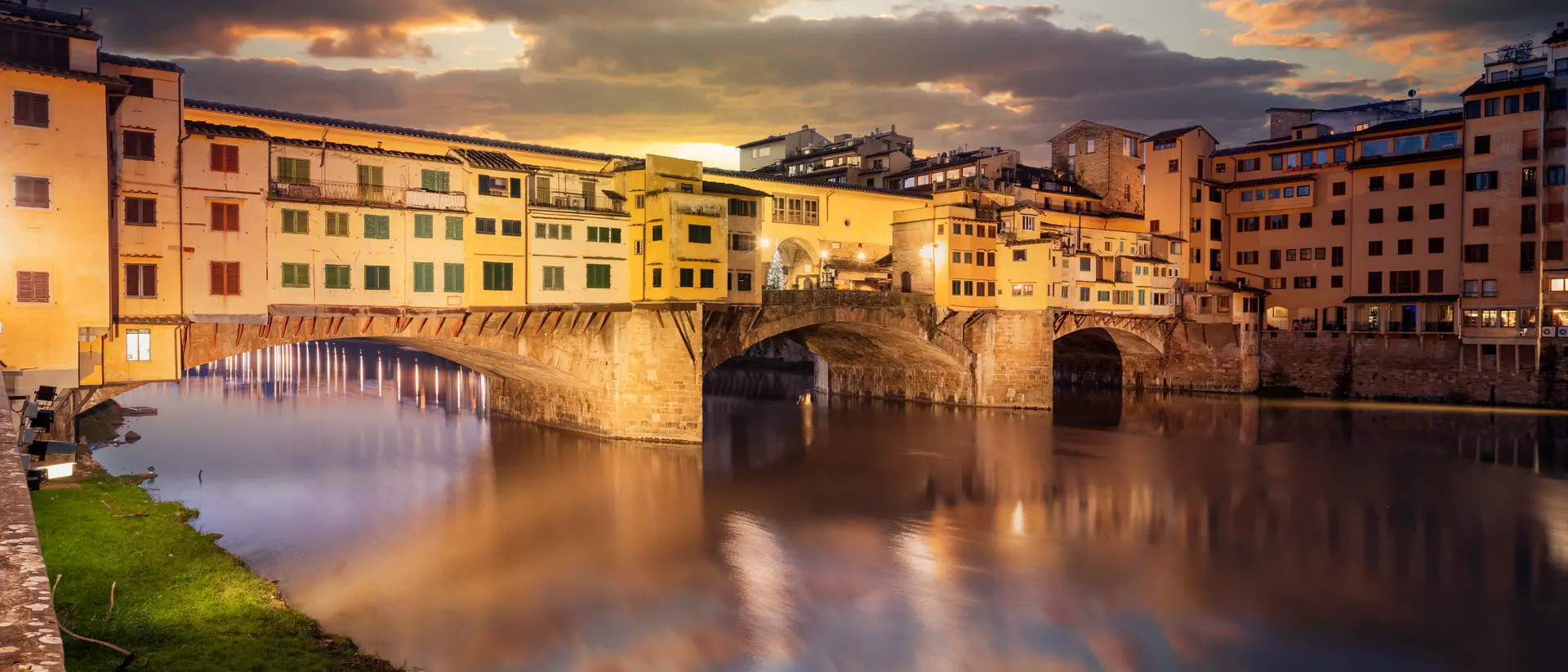 The Ponte Vecchio Bridge crossing the Arno River at twilight.