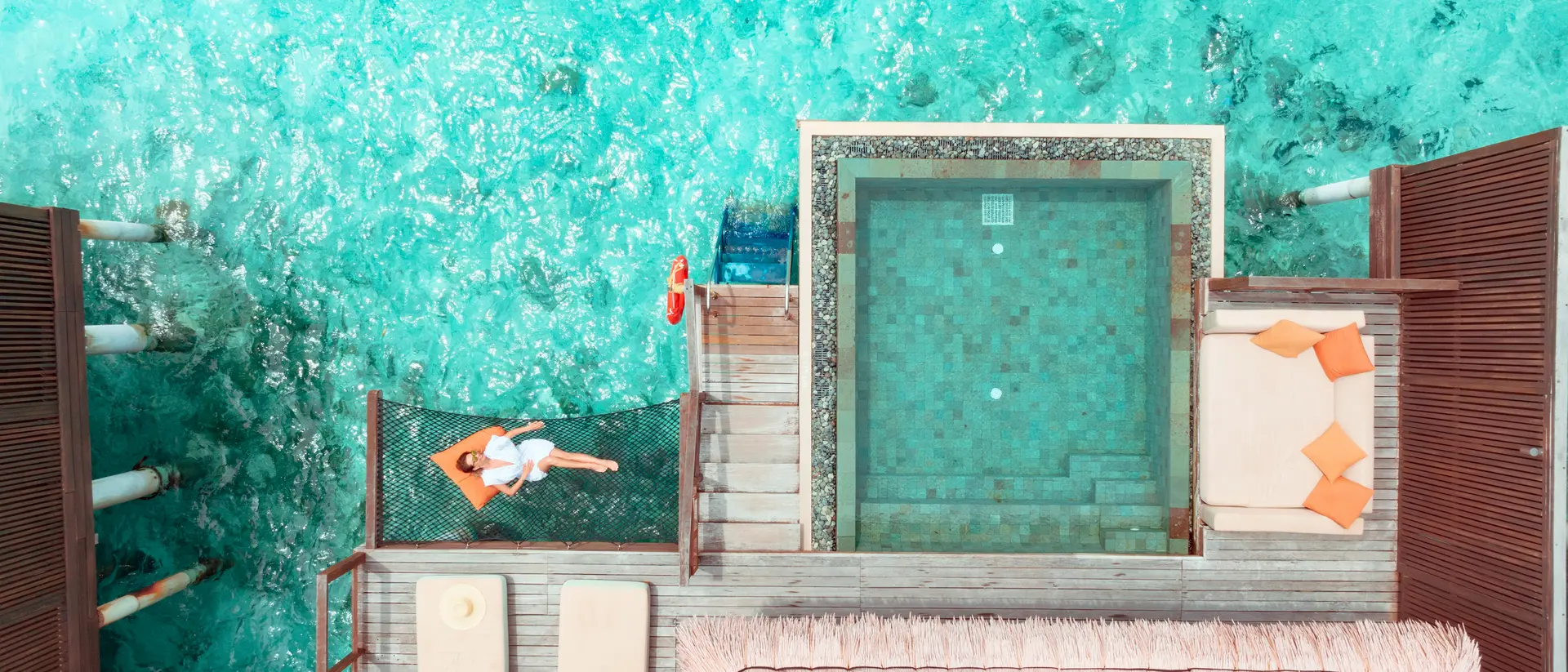 Woman lying on hammock over ocean.