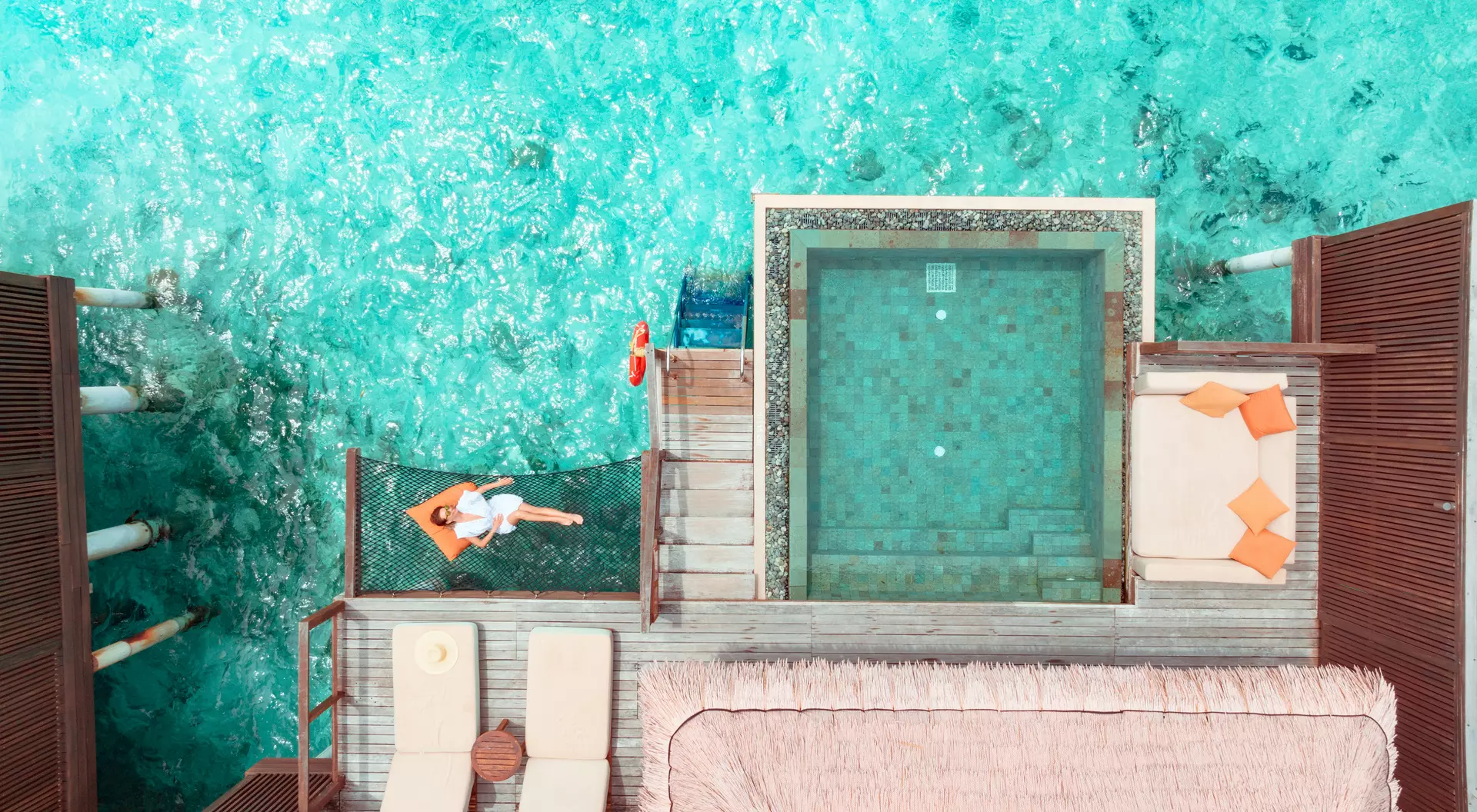 Woman lying on hammock over ocean.