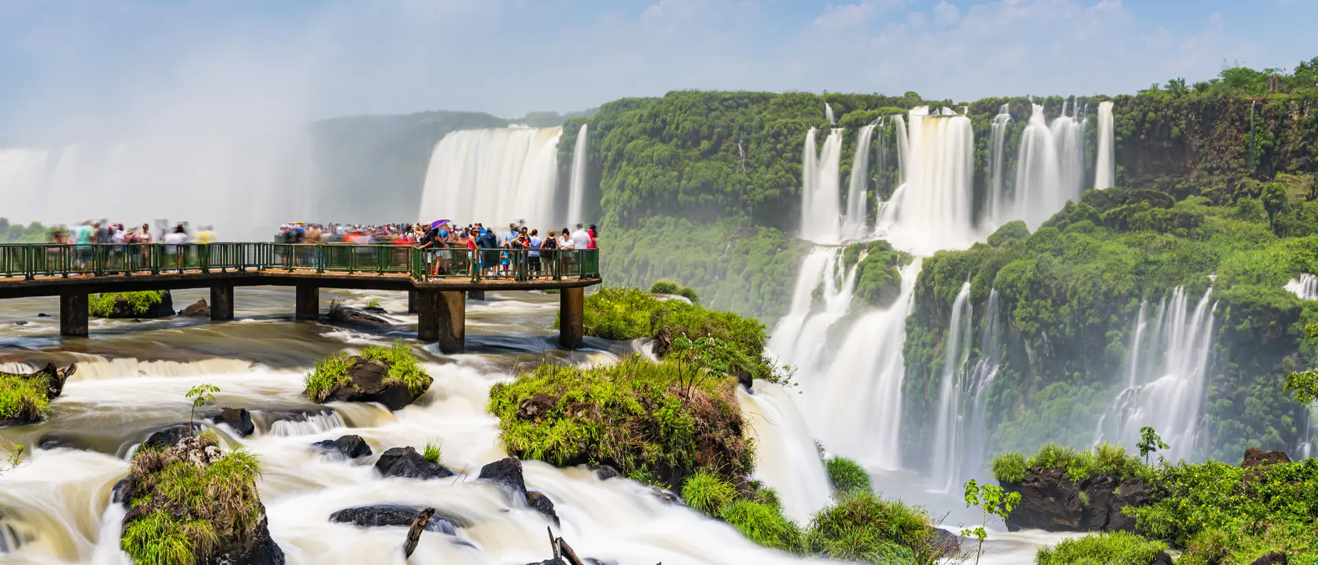 Tourists enjoying the Iguaçu Falls, Foz do Iguaçu, Parana, Brazil on the footbridge into the water on a sunny day