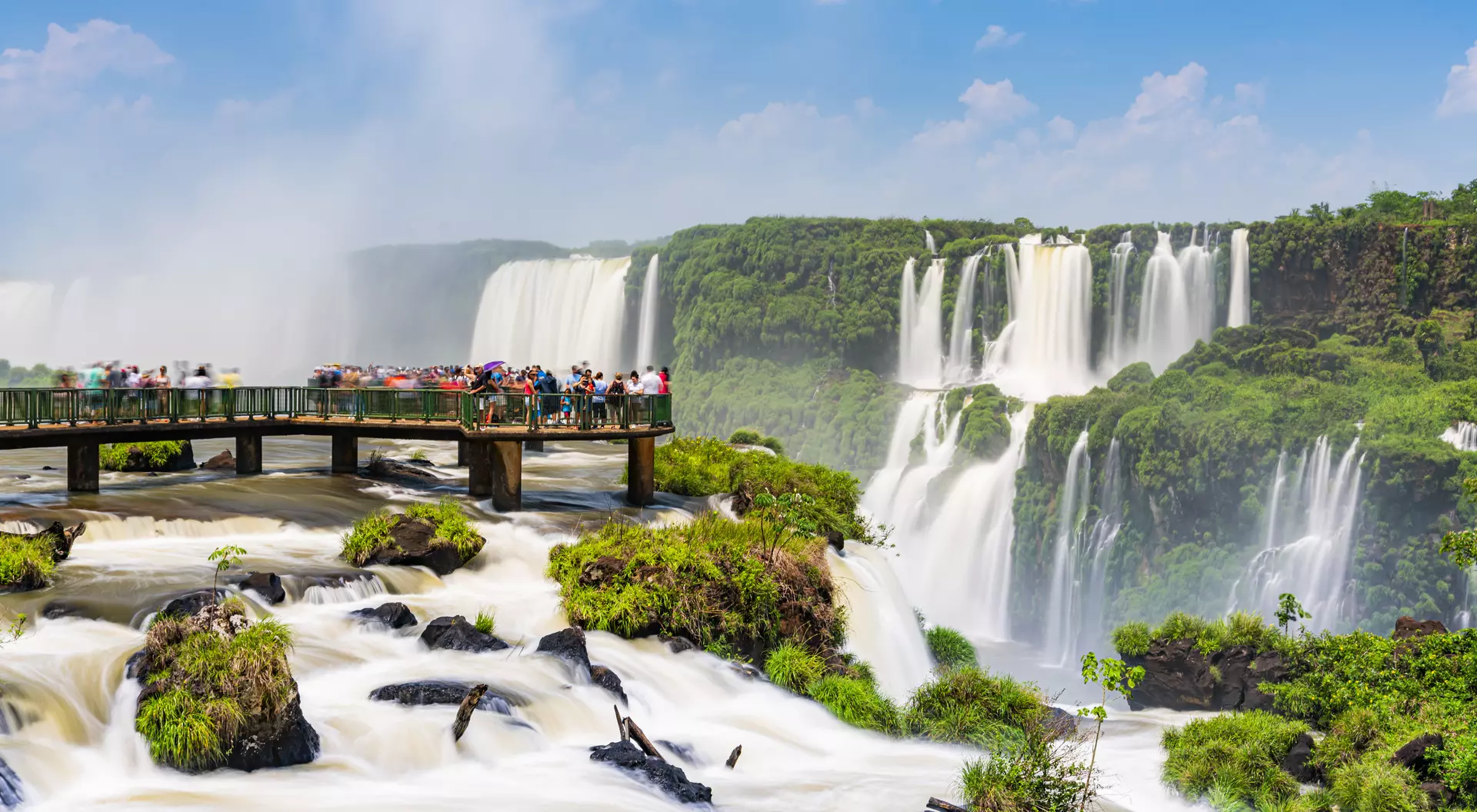 Tourists enjoying the Iguaçu Falls, Foz do Iguaçu, Parana, Brazil on the footbridge into the water on a sunny day