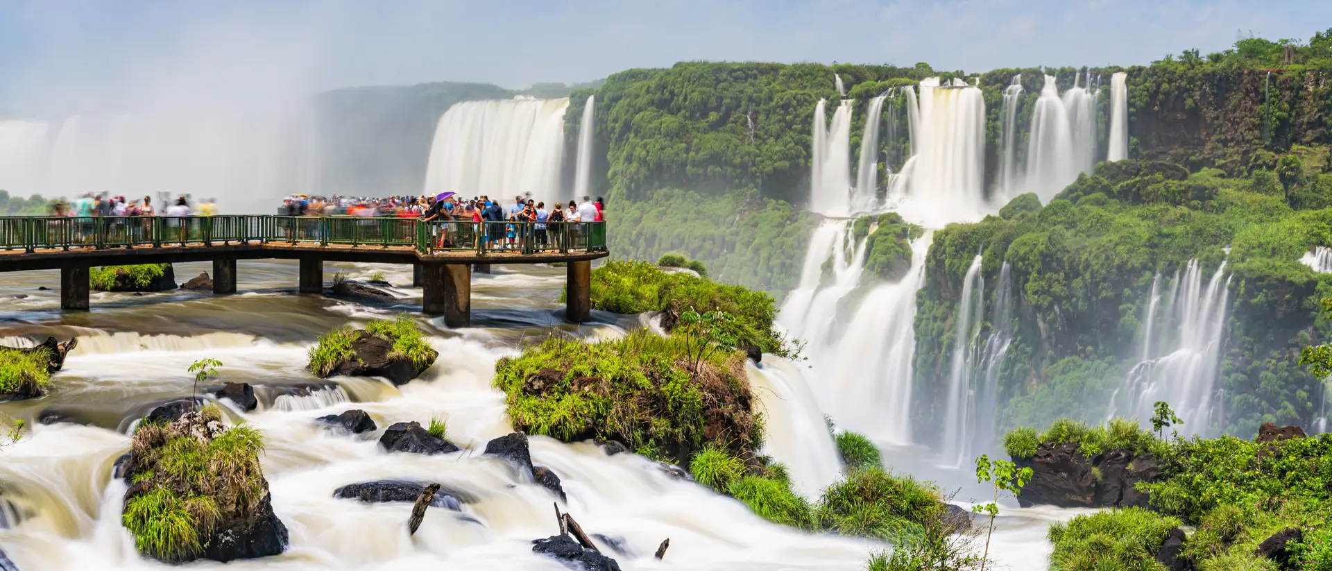 Tourists enjoying the Iguaçu Falls, Foz do Iguaçu, Parana, Brazil on the footbridge into the water on a sunny day