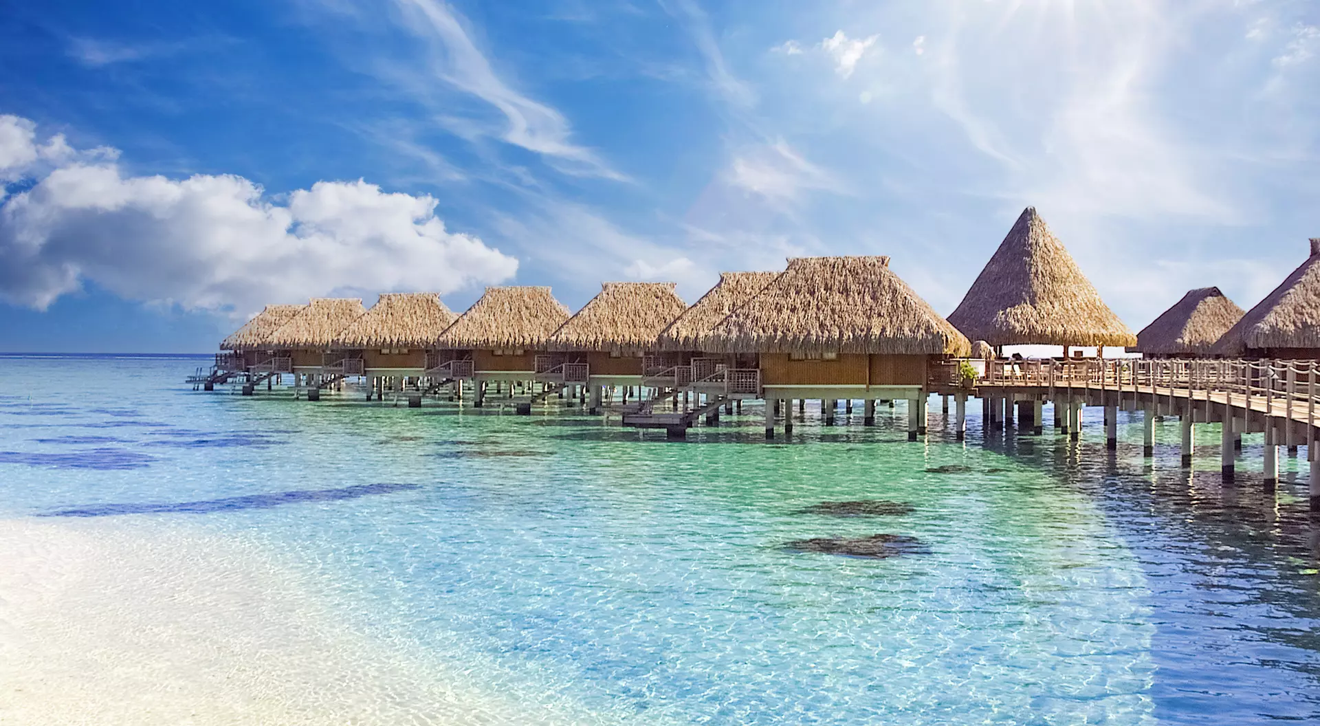 The crystal clear blue ocean waters with tropical overwater bungalows in Moorea