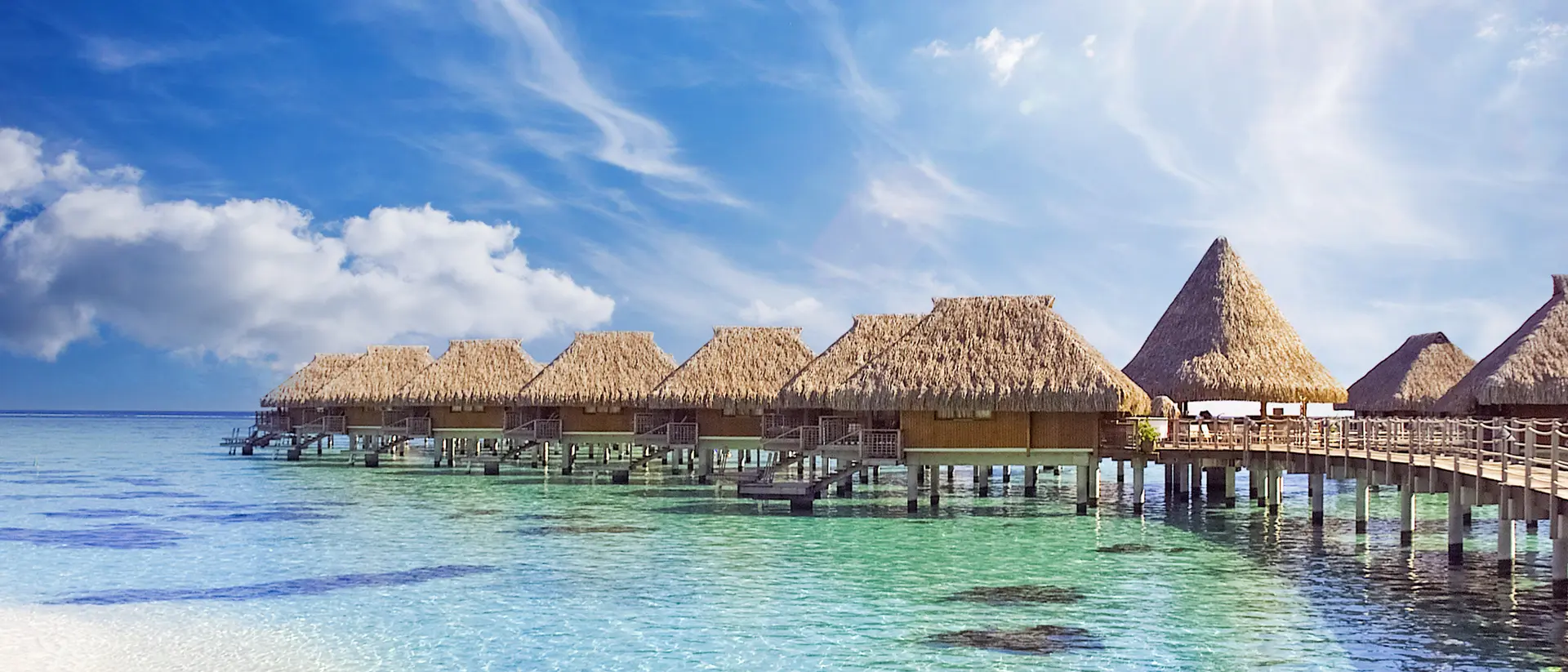 The crystal clear blue ocean waters with tropical overwater bungalows in Moorea