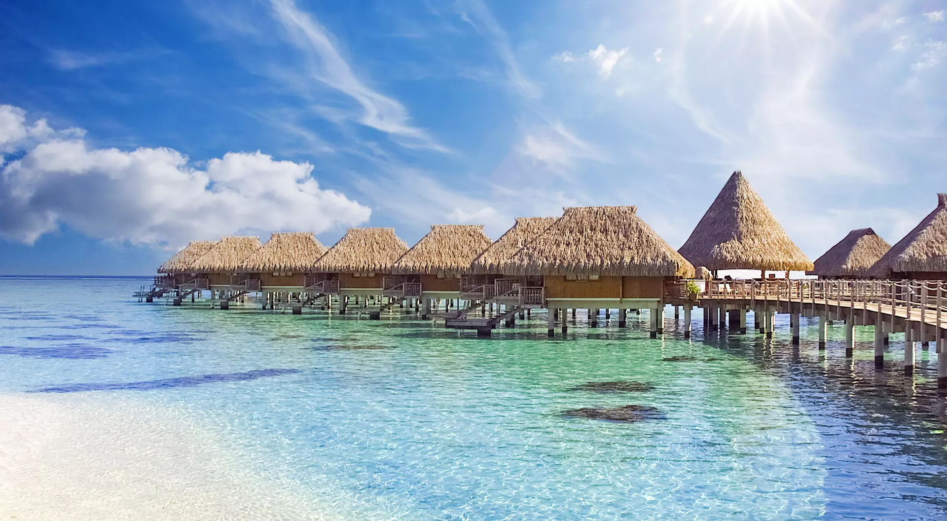 The crystal clear blue ocean waters with tropical overwater bungalows in Moorea
