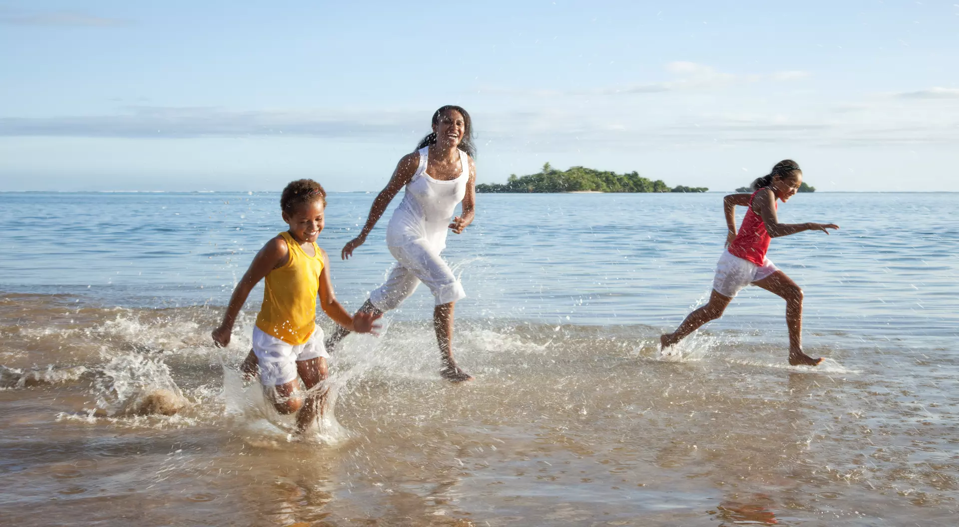 Mother and Daughters Running on Beach.