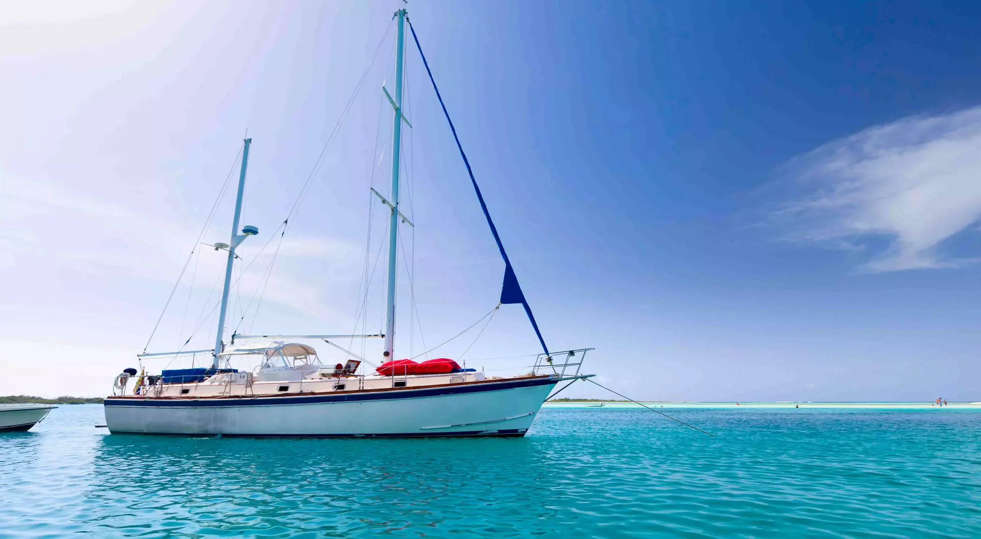 Sailboat anchored at a tropical turquoise island.