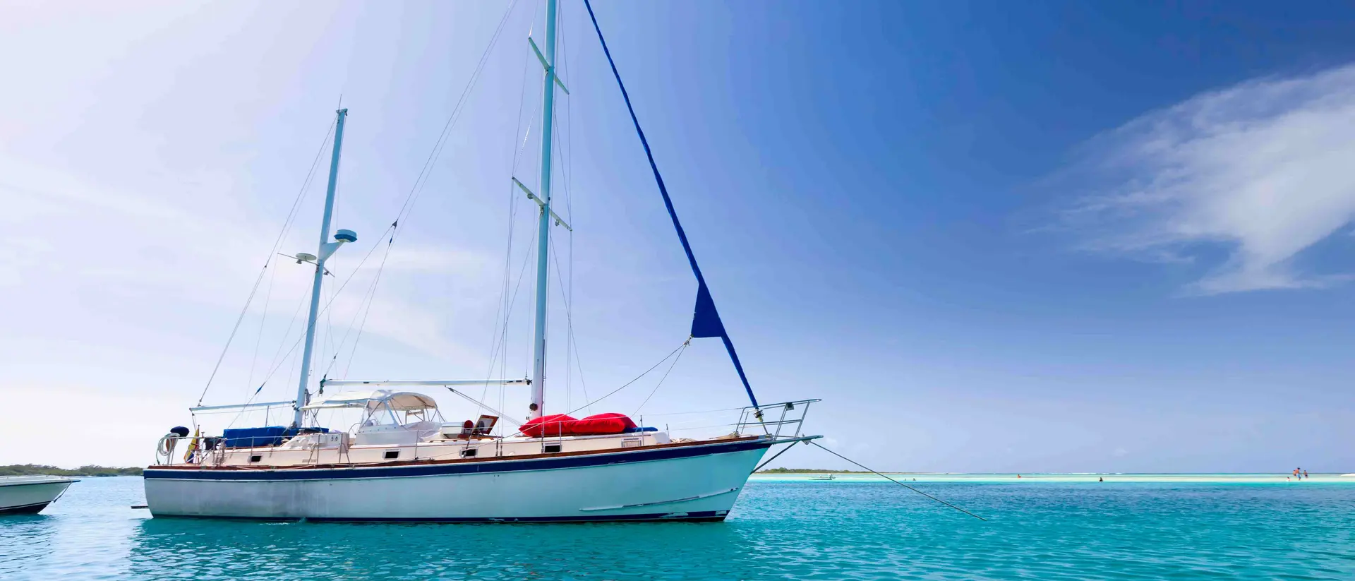 Sailboat anchored at a tropical turquoise island.