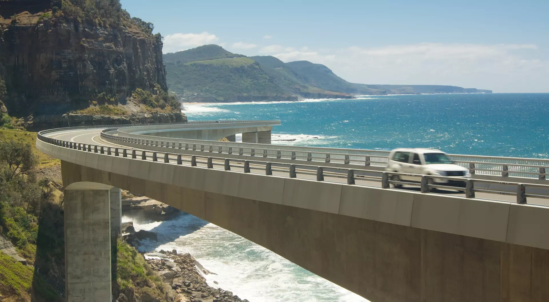A car goes across the Sea Cliff Bridge