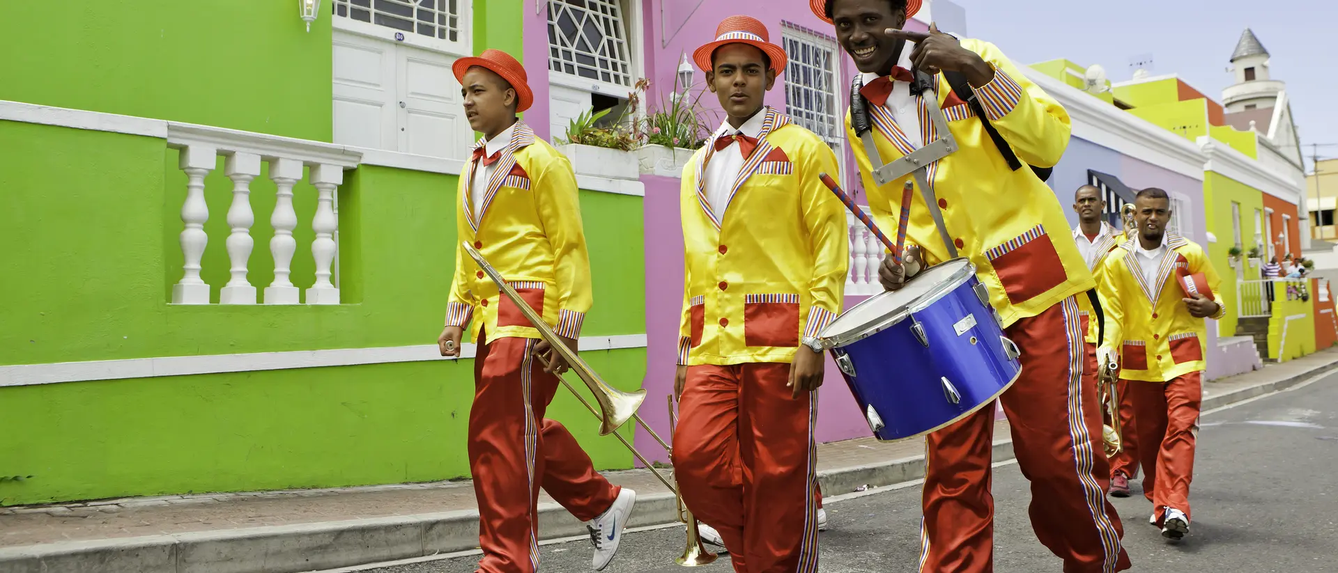 Minstrels dressed up carrying their musical instruments, trumpets and drum