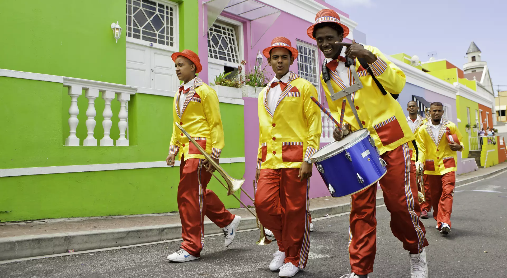 Minstrels dressed up carrying their musical instruments, trumpets and drum