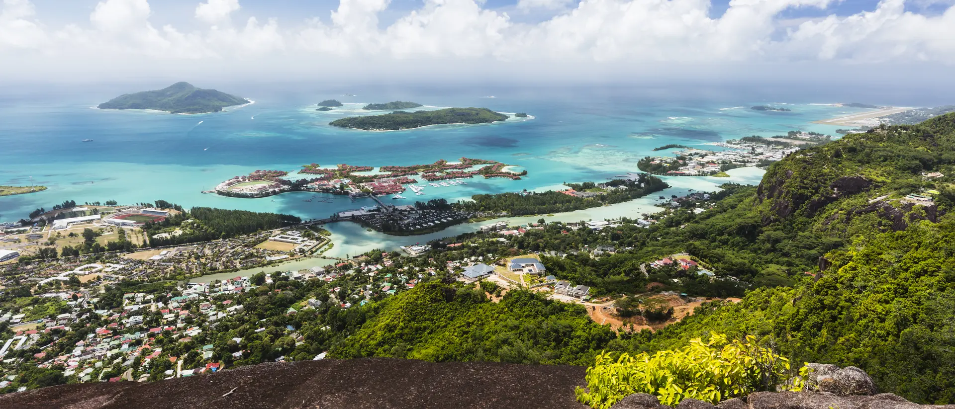 Mount Copolia over the east of Mahe, Seychelles with the capital Victoria and Eden Island, granite rock in the foreground.