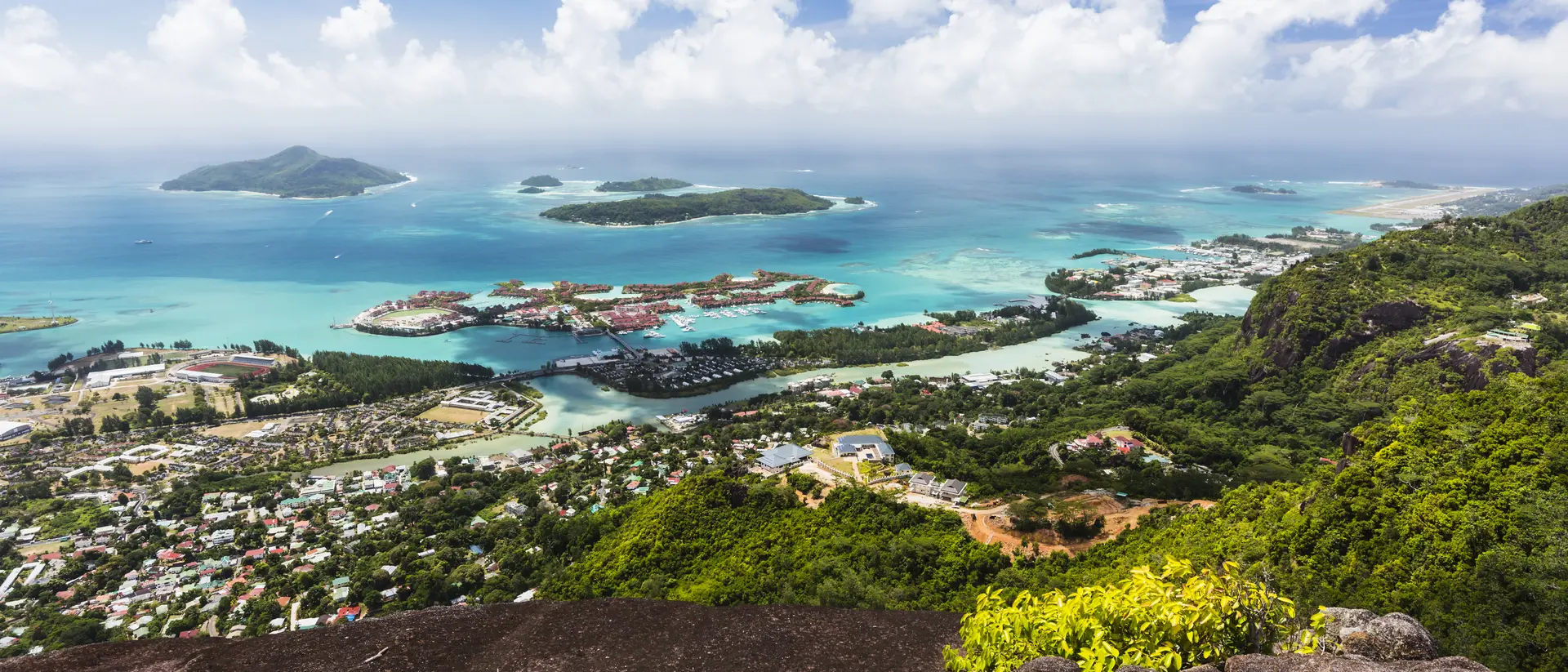 Mount Copolia over the east of Mahe, Seychelles with the capital Victoria and Eden Island, granite rock in the foreground.