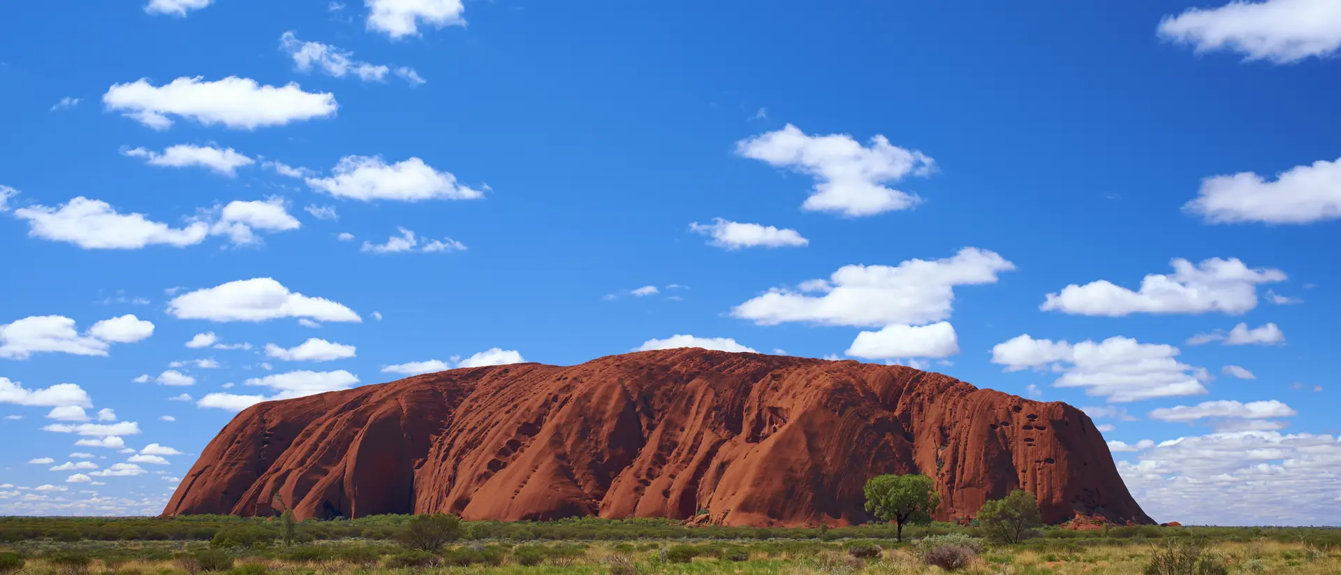 Fluffy clouds drift over Uluru (also known as Ayers Rock) in the Australian Outback. A genuine Wonder of the Natural World (and a UNESCO World Heritage Site), it's also a sacred place to the local Anangu people.